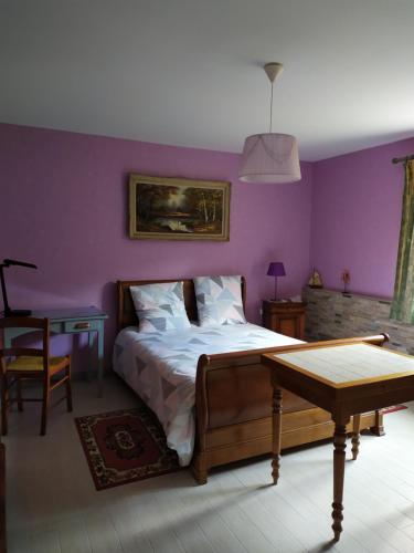 a bedroom with purple walls and a bed and a table at LES BRUYERES in Chaptelat