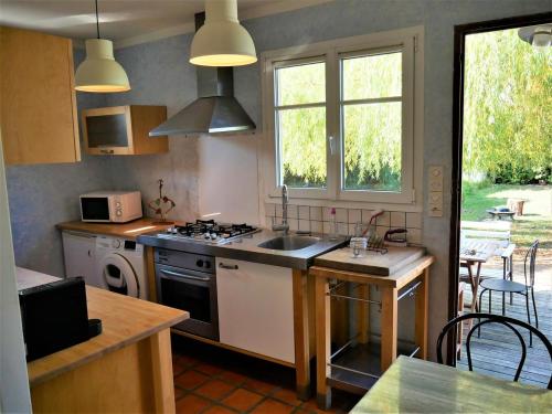 une cuisine avec un évier et une cuisinière four supérieur dans l'établissement Gîte du Loiret, à Saint-Hilaire-Saint-Mesmin