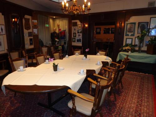 a dining room with tables and chairs and a man in the background at Hotel Wilhelmina in Venlo