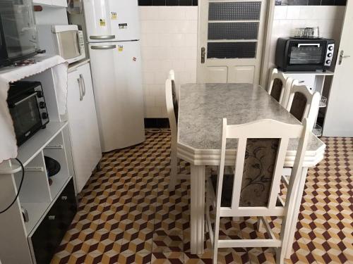 eine Küche mit einem Tisch und Stühlen sowie einem Kühlschrank in der Unterkunft Dona Maura - Hospedagem Domiciliar in Pelotas