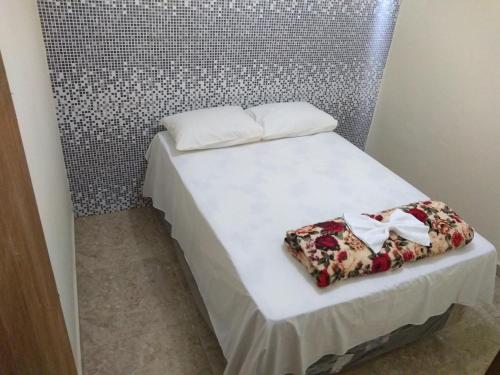 Una cama con sábanas blancas y flores. en Casa Bela Paisagem, en Mucugê