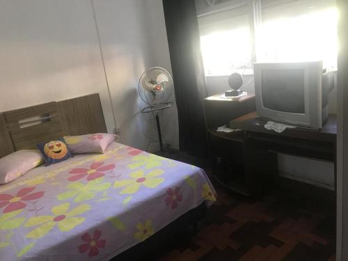 Schlafzimmer mit einem Bett, einem TV und einem Fenster in der Unterkunft Dona Maura - Hospedagem Domiciliar in Pelotas