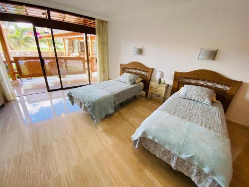 dwa łóżka w pokoju z dużym oknem w obiekcie Villa Bravo in Anfi Tauro Golf resort w mieście Mogán