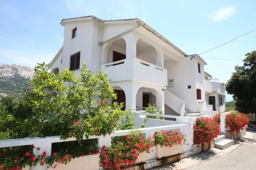 a white house with flowers on a fence at Apartments Juranić in Baška