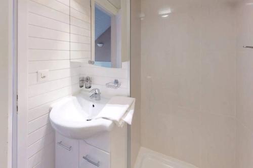 uma casa de banho branca com um lavatório e um espelho em Charmant et lumineux appartement Duplex à Charmey em Charmey