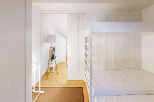 Dormitorio blanco con litera y pasillo en Charmant et lumineux appartement Duplex à Charmey en Charmey