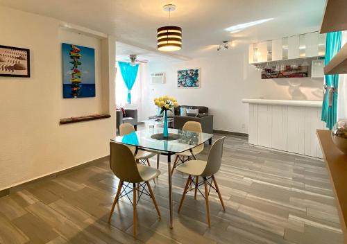a dining room and kitchen with a glass table and chairs at Departamento Tucán in Cancún