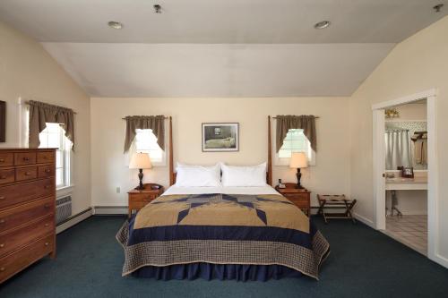 a bedroom with a bed with two night stands and two lamps at Country Inn at Camden Rockport in Rockport