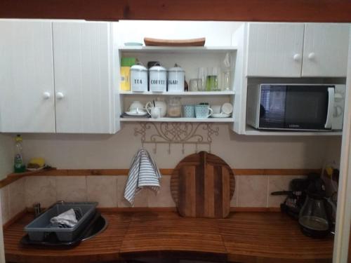 a kitchen with white cabinets and a microwave at Sol Y Sombra in Bettyʼs Bay