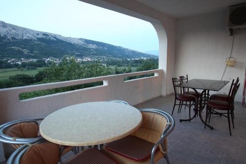 a balcony with a table and chairs and a view of a mountain at Apartments Juranić in Baška