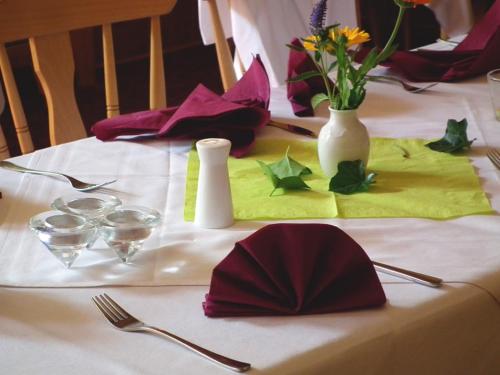 einen Tisch mit einem weißen Tischtuch mit Blumen darauf in der Unterkunft Gasthaus & Hotel Zur Linde in Friedrichroda