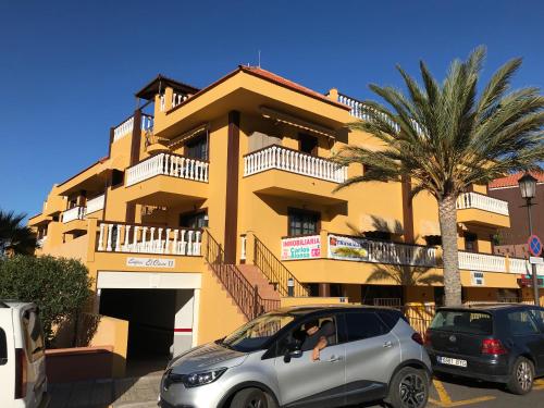 two cars parked in front of a yellow building at Holiday in Playa Calera - Swimming pool in Valle Gran Rey