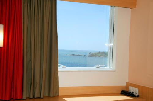 a window with a view of the ocean at ibis Vitoria Praia de Camburi in Vitória