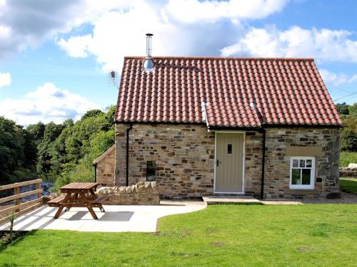 a stone house with a picnic table and a bench at Plum Tree Cottage in Witton le Wear