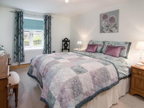 Un dormitorio con una cama grande y una ventana en Chatton Cottage, en Chatton