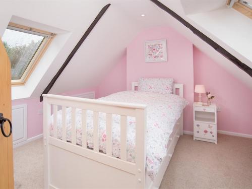 a pink and white bedroom with a bed and a window at Chatton Cottage in Chatton