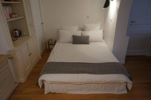 ein Schlafzimmer mit einem großen Bett mit weißer Bettwäsche und Kissen in der Unterkunft Le calme à 2 pas de Paris in Levallois-Perret