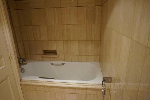 La salle de bains carrelée est pourvue d'une baignoire. dans l'établissement Le calme à 2 pas de Paris, à Levallois-Perret