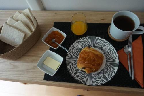 einen Tisch mit einem Teller Essen und einem Glas Orangensaft in der Unterkunft Le calme à 2 pas de Paris in Levallois-Perret
