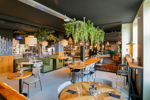 a restaurant with wooden tables and chairs and plants at Hotel Marktstad in Schagen