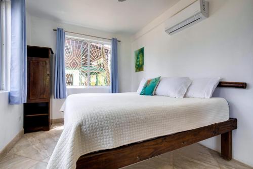
a bedroom with a bed and a window at Driftwood Gardens Guesthouse in Placencia
