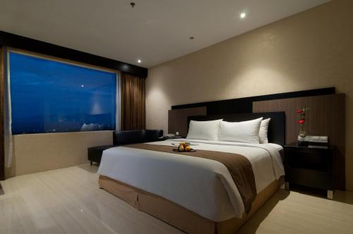 a bedroom with a large bed and a large window at Aria Gajayana in Malang