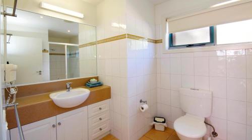 a bathroom with a toilet, sink, and mirror at Anchorage Motel & Villas Lorne in Lorne