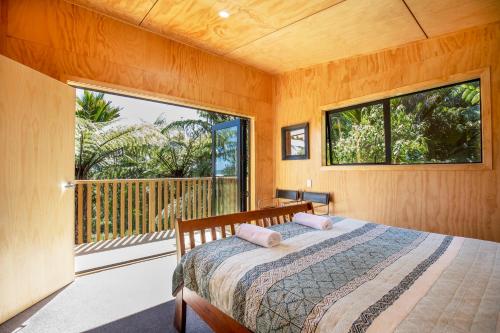 a bedroom with a bed and a large window at Treescapes in Punakaiki