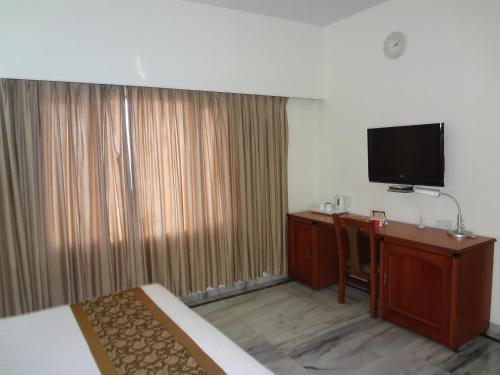 a hotel room with a bed and a desk and a television at Daspalla Executive Court in Visakhapatnam