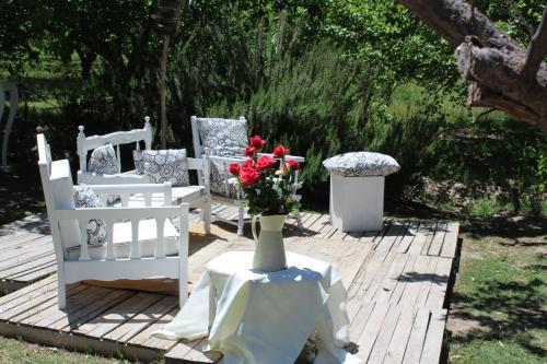 a group of white chairs and a vase with flowers on a table at Finca La Celestita in Colonia Alvear