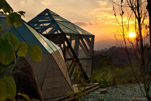 a glass house with the sunset in the background at Nacimiento Glamping in San Agustín