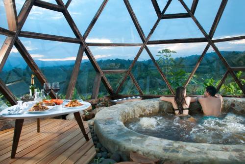 聖奧古斯丁的住宿－Nacimiento Glamping，两人坐在玻璃圆顶的热水浴缸中