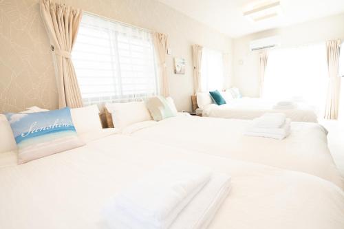 a white room with two beds and a couch at ホテルトーマスみなみ in Itoman