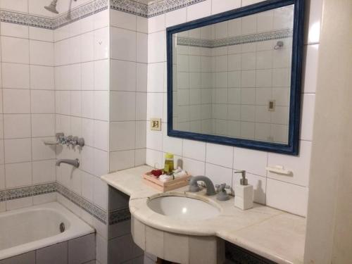 a bathroom with a sink and a tub and a mirror at VEINTICINCO Casa de Huéspedes in Mendoza