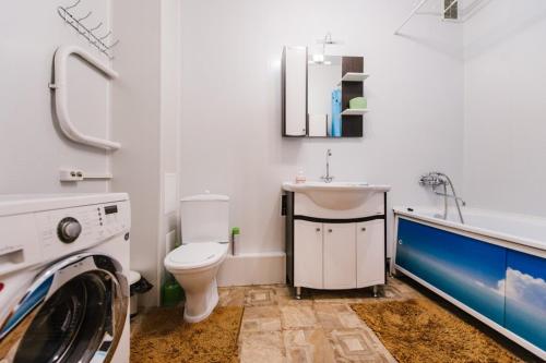 a bathroom with a toilet and a sink and a washing machine at Dekabrist Apartment at Kirova 16 in Chita