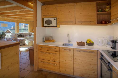 une cuisine avec des placards en bois et un salon dans l'établissement Chalet Alpachic - OVO Network, à La Clusaz