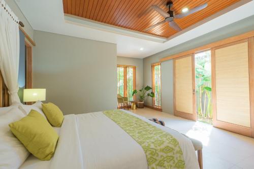 ein Schlafzimmer mit einem Bett und einem Deckenventilator in der Unterkunft Villa Daun Canggu by Premier Hospitality Asia in Canggu
