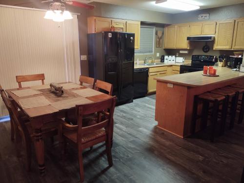 a kitchen with a wooden table and a black refrigerator at 2BR Gated Escape With A Pool And Walk to Dining and Trails in Pinetop-Lakeside
