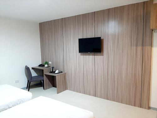 een hotelkamer met een tv aan een houten muur bij Anex Hotel near US Embassy in Manilla