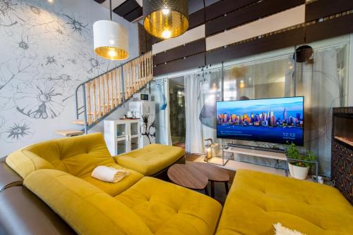a living room with a yellow couch and a tv at Inn OZZ in Karagandy