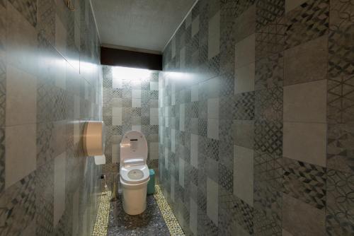 a bathroom with a toilet and a tiled wall at Inn OZZ in Karagandy