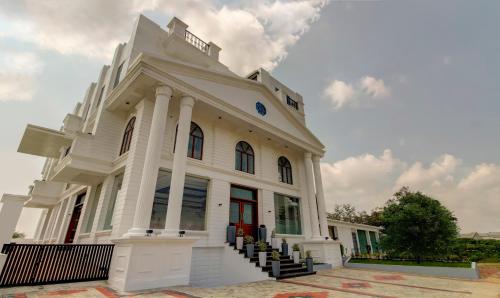 a large white building with a red door at Treebo The Meridian in Chikmagalūr