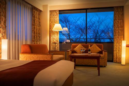 una camera d'albergo con un letto, sedie e una finestra di Hotel Io Alpheratz a Kasama