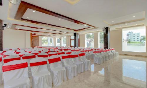 a banquet hall with white and red chairs and tables at Treebo The Meridian in Chikmagalūr