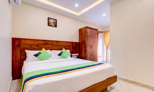 a bedroom with a large white bed with colorful pillows at Treebo The Meridian in Chikmagalūr