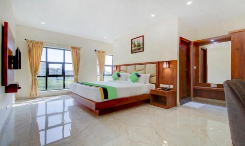 a bedroom with a bed and a large window at Treebo The Meridian in Chikmagalūr