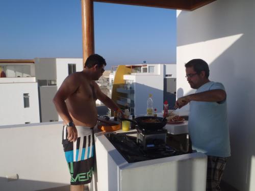 Dois homens numa cozinha a preparar comida. em Paracas top tower beach front em Paracas