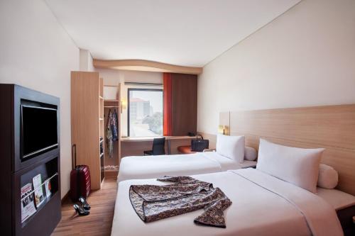 a hotel room with two beds and a flat screen tv at Sentral Cawang Hotel in Jakarta