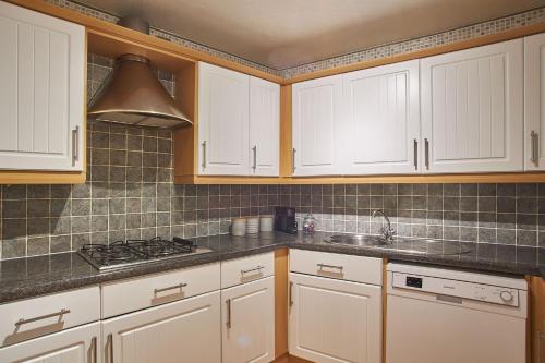 a kitchen with white cabinets and a sink at Host & Stay - Regency Mansions Apartment in Redcar
