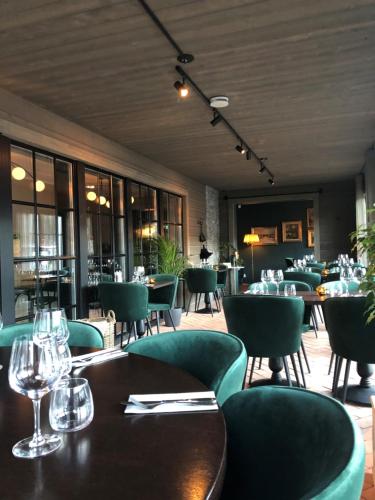 um restaurante com cadeiras verdes, mesas e copos em Hotell Viktors em Sälen
